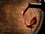 Close up of wine being poured with a wine barrel in the background.