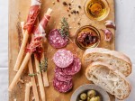 Bread sticks with ham and salami on wooden background